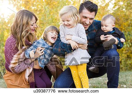Stock Photograph - "Happy family with tree children (6-11 months, 2-3, 4-5) playing in park". Fotosearch
