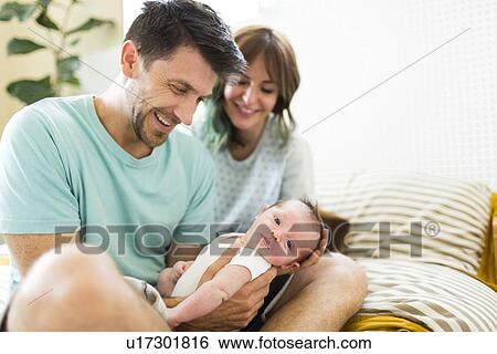 Stock Photograph - Happy parents looking at baby boy (6-11 months). Fotosearch