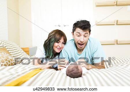 Happy parents playing with baby boy (6-11 months) on bed View Large Photo Image Stock Image - Happy parents playing with baby boy (6-11 months) on bed. Fotosearch