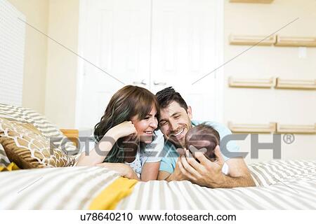 Happy parents playing with baby boy (6-11 months) on bed View Large Photo Image Stock Image - Happy parents playing with baby boy (6-11 months) on bed. Fotosearch