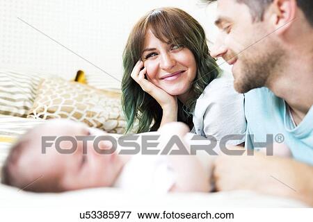 Happy parents with baby boy (6-11 months) on bed View Large Photo Image Stock Photo - Happy parents with baby boy (6-11 months) on bed. Fotosearch