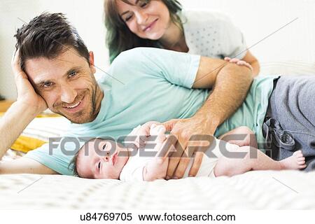 Happy parents with baby boy (6-11 months) lying on bed View Large Photo Image Stock Photography - Happy parents with baby boy (6-11 months) lying on bed. Fotosearch