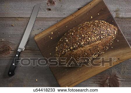 Stock Image - Kitchen knife and loaf of bread on wooden table. Fotosearch