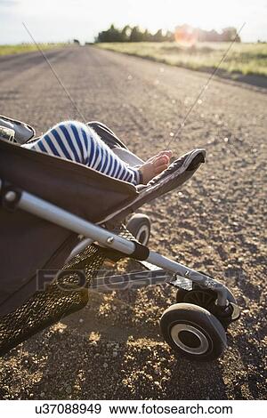 Stock Photo - Low-section of baby girl (6-11 months) in stroller. Fotosearch