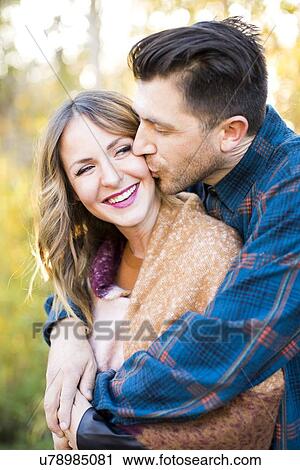 Stock Image - Man kissing smiling woman. Fotosearch