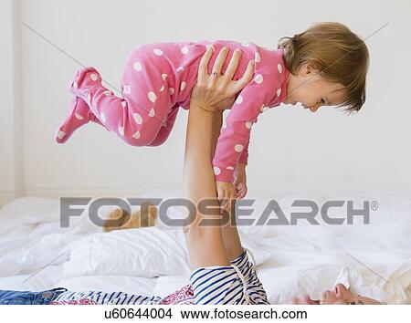 Picture - Mother playing with girl (2-3) on bed. Fotosearch