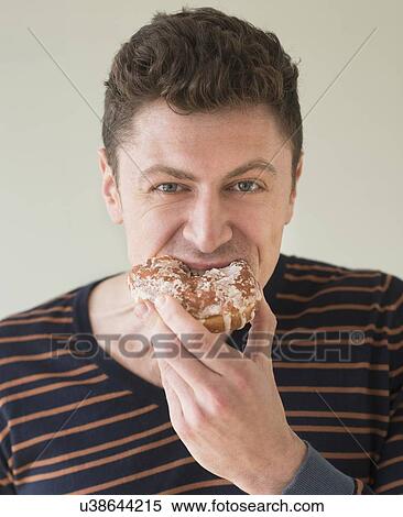 Stock Photography - Portrait of man eating donut. Fotosearch