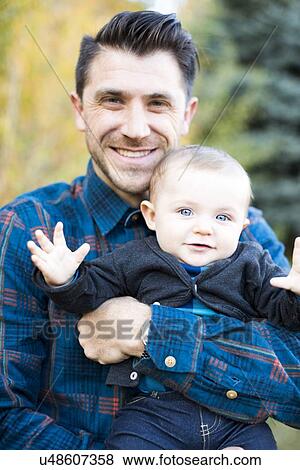 Stock Photo - Portrait of smiling man with little son (6-11 months). Fotosearch