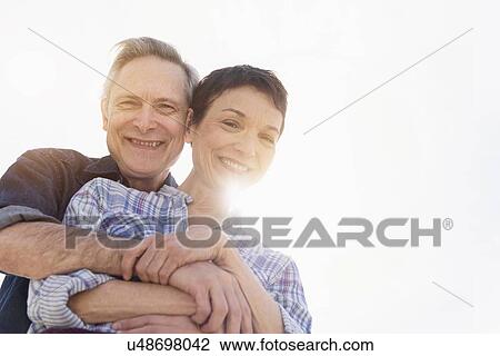 Portrait of smiling senior couple embracing in sunlight View Large Photo Image Stock Image - Portrait of smiling senior couple embracing in sunlight. Fotosearch