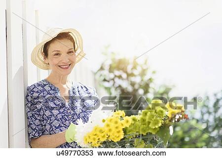 Stock Image - Portrait of smiling senior woman with flowers. Fotosearch