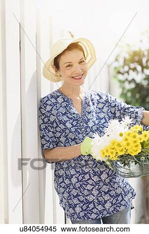 Stock Photography - Portrait of smiling senior woman with flowers. Fotosearch