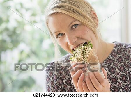 Stock Photo - Portrait of woman eating sandwich. Fotosearch