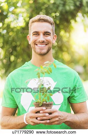 Portrait of young man holding potted plant View Large Photo Image Stock Image - Portrait of young man holding potted plant. Fotosearch