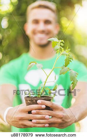 Portrait of young man holding potted plant View Large Photo Image Stock Photo - Portrait of young man holding potted plant. Fotosearch