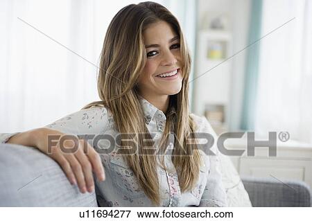 Portrait of young woman sitting on sofa View Large Photo Image Stock Photo - Portrait of young woman sitting on sofa. Fotosearch