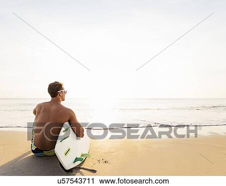 Rear view of surfer on beach View Large Photo Image Stock Image - Rear view of surfer on beach. Fotosearch