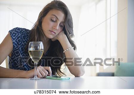 Sad woman with glass of wine texting View Large Photo Image Picture - Sad woman with glass of wine texting. Fotosearch