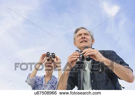 Stock Photograph - Senior couple watching birds with binoculars. Fotosearch