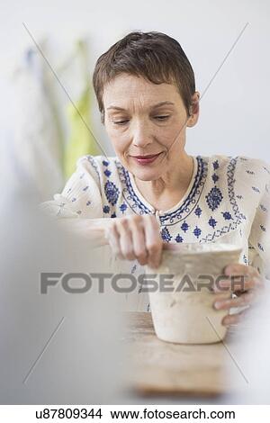 Picture - Senior woman making flower pot at workshop. Fotosearch