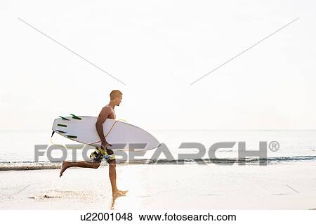 Side-view of surfer running View Large Photo Image Stock Photo - Side-view of surfer running. Fotosearch