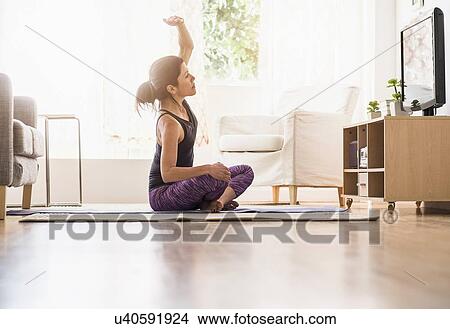 Side-view of woman exercising in living room View Large Photo Image Picture - Side-view of woman exercising in living room. Fotosearch