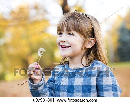 Stock Image - Smiling girl (4-5) with dandelion. Fotosearch