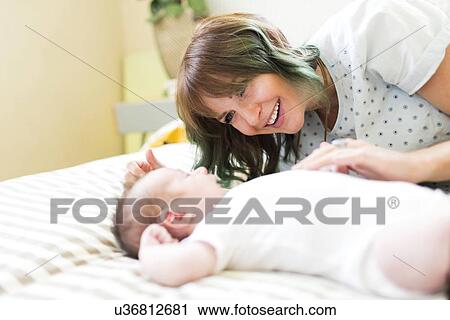Smiling mother lying on bad with baby boy (6-11 months) View Large Photo Image Stock Image - Smiling mother lying on bad with baby boy (6-11 months). Fotosearch