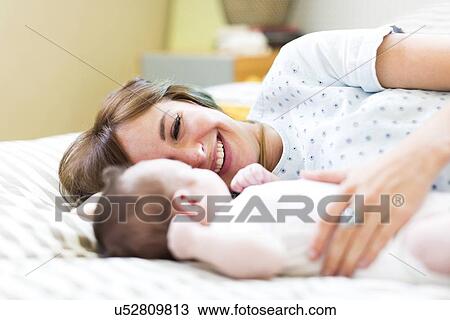 Smiling mother lying on bad with baby boy (6-11 months) View Large Photo Image Stock Image - Smiling mother lying on bad with baby boy (6-11 months). Fotosearch