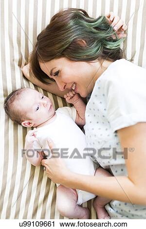 Smiling mother lying on bad with baby boy (6-11 months) View Large Photo Image Stock Image - Smiling mother lying on bad with baby boy (6-11 months). Fotosearch