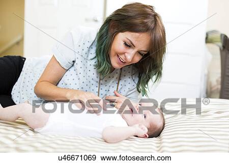 Smiling mother lying on bad with baby boy (6-11 months) View Large Photo Image Stock Photo - Smiling mother lying on bad with baby boy (6-11 months). Fotosearch
