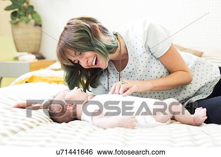 Smiling mother lying on bad with baby boy (6-11 months) View Large Photo Image Stock Photograph - Smiling mother lying on bad with baby boy (6-11 months). Fotosearch