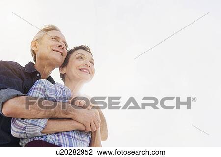 Smiling senior couple embracing in sunlight View Large Photo Image Stock Image - Smiling senior couple embracing in sunlight. Fotosearch