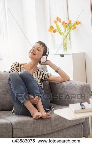 Smiling senior woman with headphones sitting on sofa View Large Photo Image Stock Photography - Smiling senior woman with headphones sitting on sofa. Fotosearch