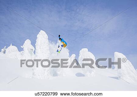 Stock Photo - Snowboarder jumping over snowy tree. Fotosearch