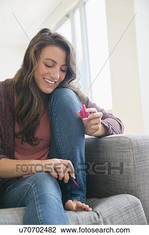 Stock Image - Woman applying nail polish on her toes. Fotosearch