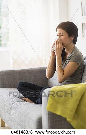 Woman blowing her nose on sofa View Large Photo Image Stock Photo - Woman blowing her nose on sofa. Fotosearch