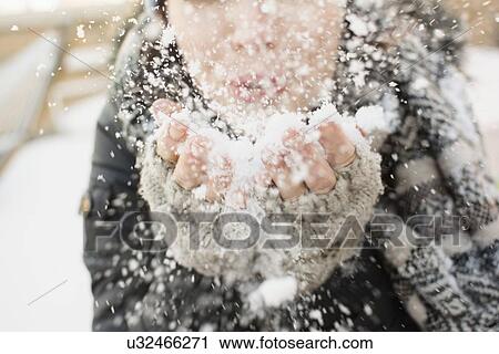 Stock Image - Woman blowing snow towards camera. Fotosearch