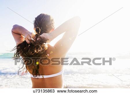 Stock Image - Woman braiding her hair on beach. Fotosearch