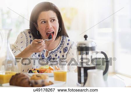 Stock Photo - Woman eating blackberries for breakfast. Fotosearch