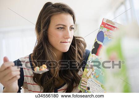 Woman eating cereal reading info on box View Large Photo Image Stock Image - Woman eating cereal reading info on box. Fotosearch