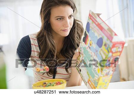 Woman eating cereal reading info on box View Large Photo Image Stock Image - Woman eating cereal reading info on box. Fotosearch