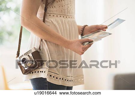 Picture - Woman holding antique camera and pictures. Fotosearch