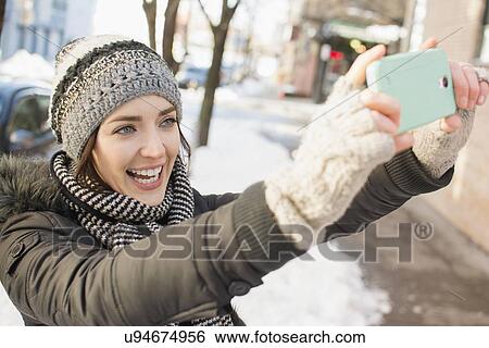 Stock Photograph - Woman in street taking selfie. Fotosearch