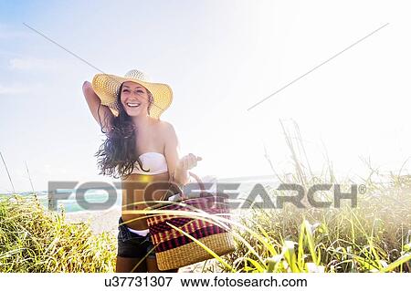 Woman in sunhat carrying basket on beach View Large Photo Image Stock Photo - Woman in sunhat carrying basket on beach. Fotosearch