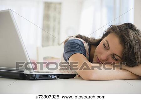 Woman leaning next to laptop View Large Photo Image Stock Photograph - Woman leaning next to laptop . Fotosearch