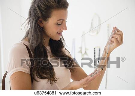 Woman looking at necklace in store View Large Photo Image Stock Image - Woman looking at necklace in store. Fotosearch