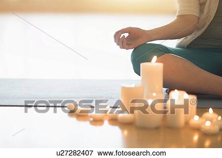 Stock Photo - Woman meditating surrounded by candles. Fotosearch
