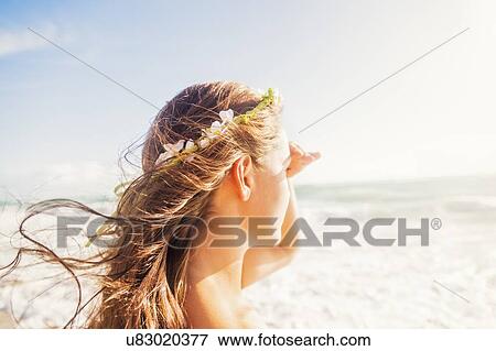 Stock Photo - Woman on beach shielding eyes. Fotosearch