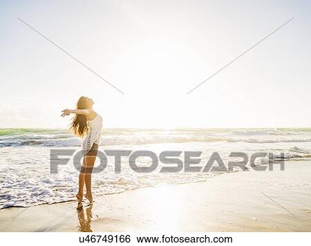 Woman on beach with arms raised View Large Photo Image Stock Photograph - Woman on beach with arms raised. Fotosearch