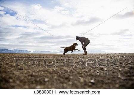 Stock Image - Woman playing with dog outdoors. Fotosearch